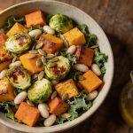 Fall salad with roasted vegetables: butternut squash, sweet potato and halved Brussels sprouts tipped hot over torn kale, with whole white beans and a jug of cider vinaigrette alongside.