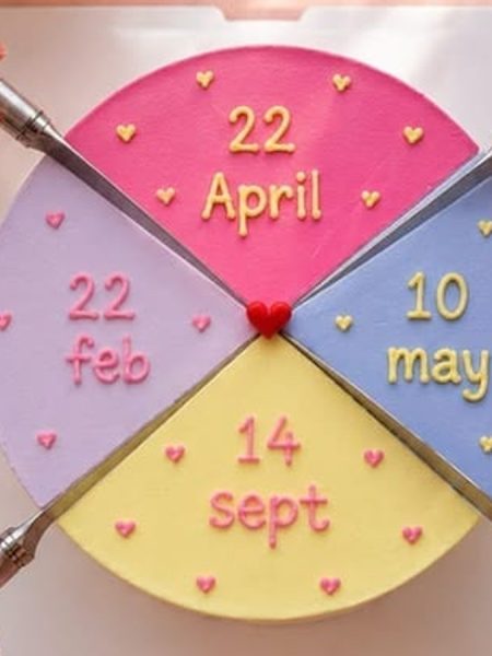 Not too sweet buttercream birthday cake, seen from above: four colored quarters, a different date piped on each, and four hands cutting with four knives.