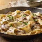 Vegan mushroom stroganoff in a skillet: pappardelle in a pale silken tofu sauce with browned cremini mushrooms and parsley